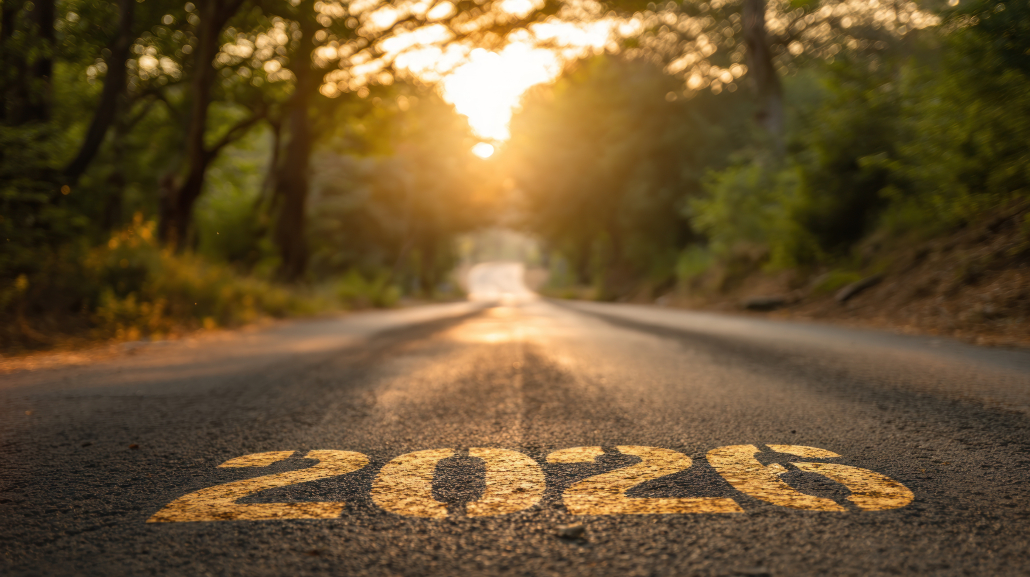 Close-up view of a road with a large painted speed limit marking on the asphalt, sunlit trees in the background at sunset.